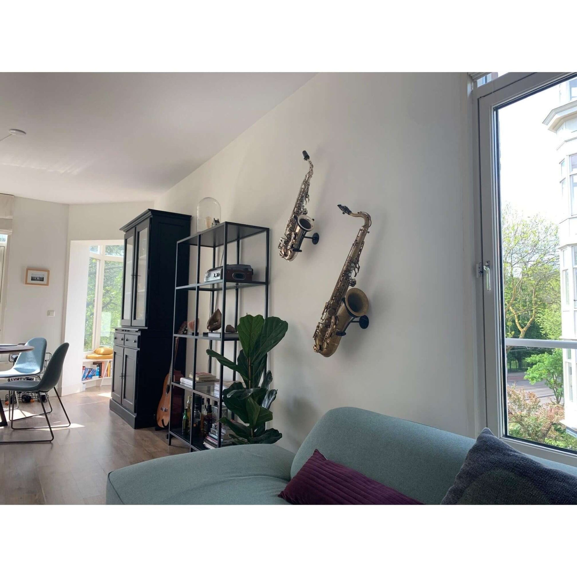 bright livingroom with sofa and wall adorned with two saxophones in Locoparasaxo stands next to cupboard and guitar